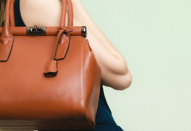 Elegant outfit. Brown leather bag in female hand boring outfit accessorizing