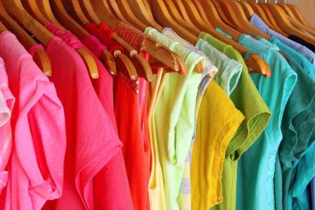 Colorful clothes on hangers in wardrobe