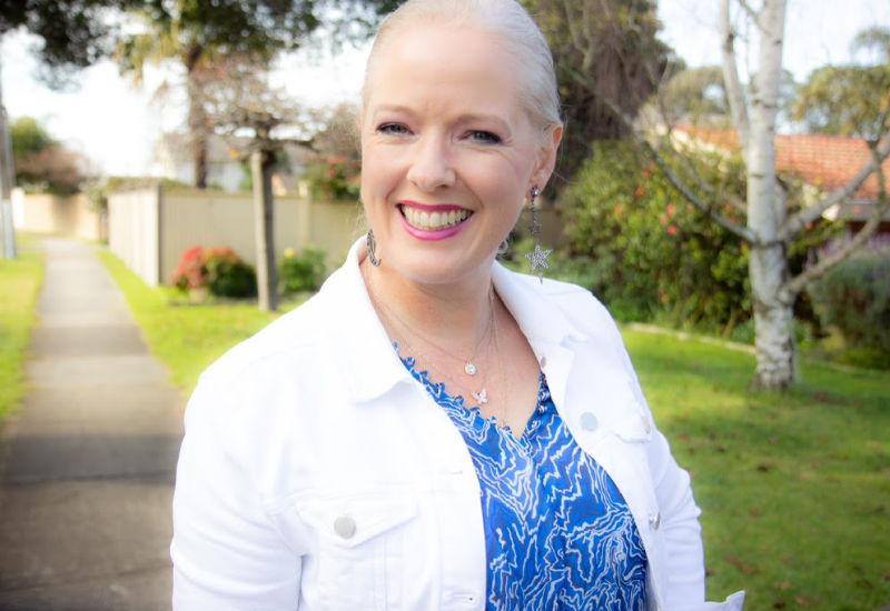 Woman wearing white denim jacket and blue top with patterns